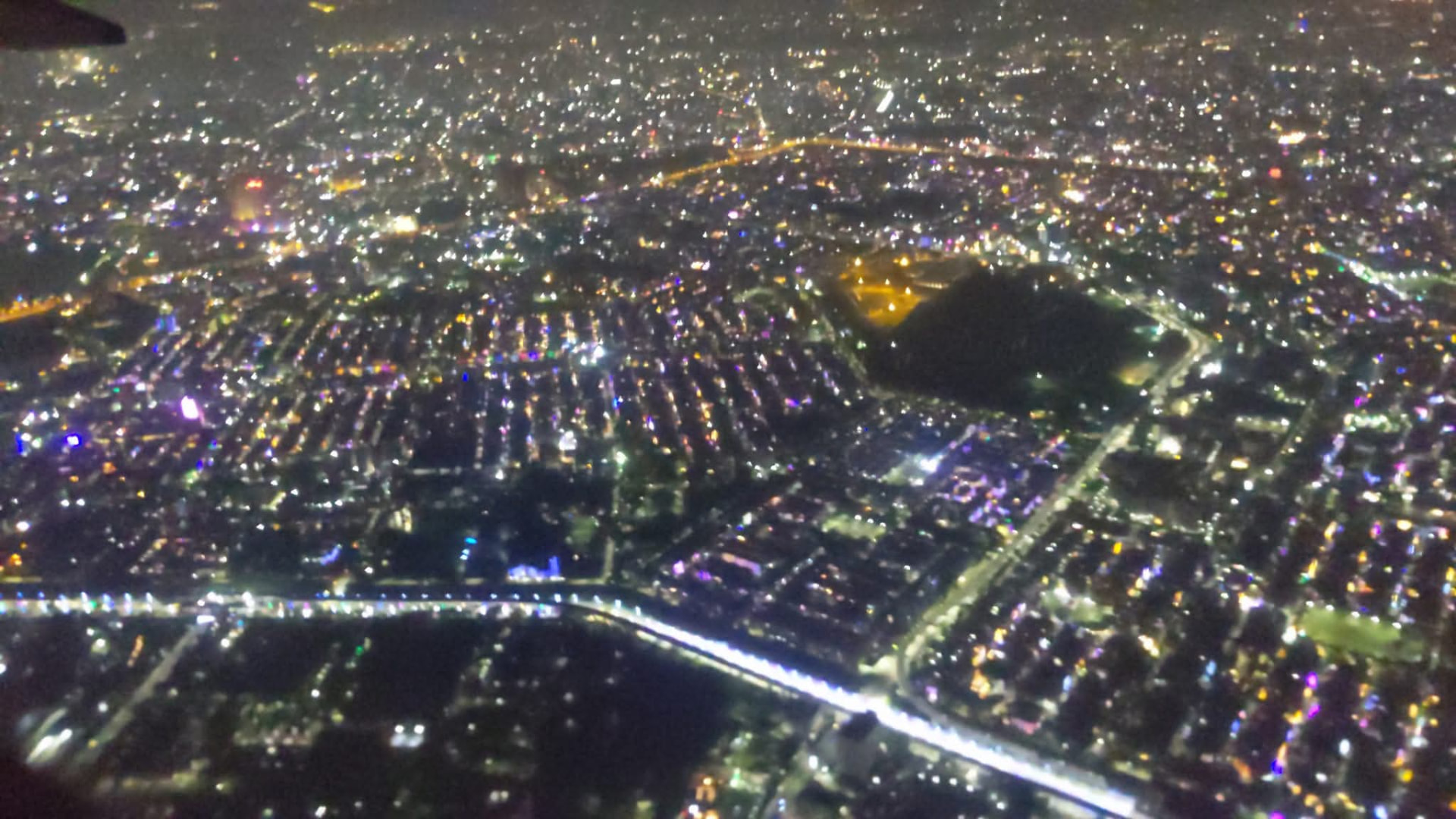 Aerial night view of a city lit up, seen from the aircraft window