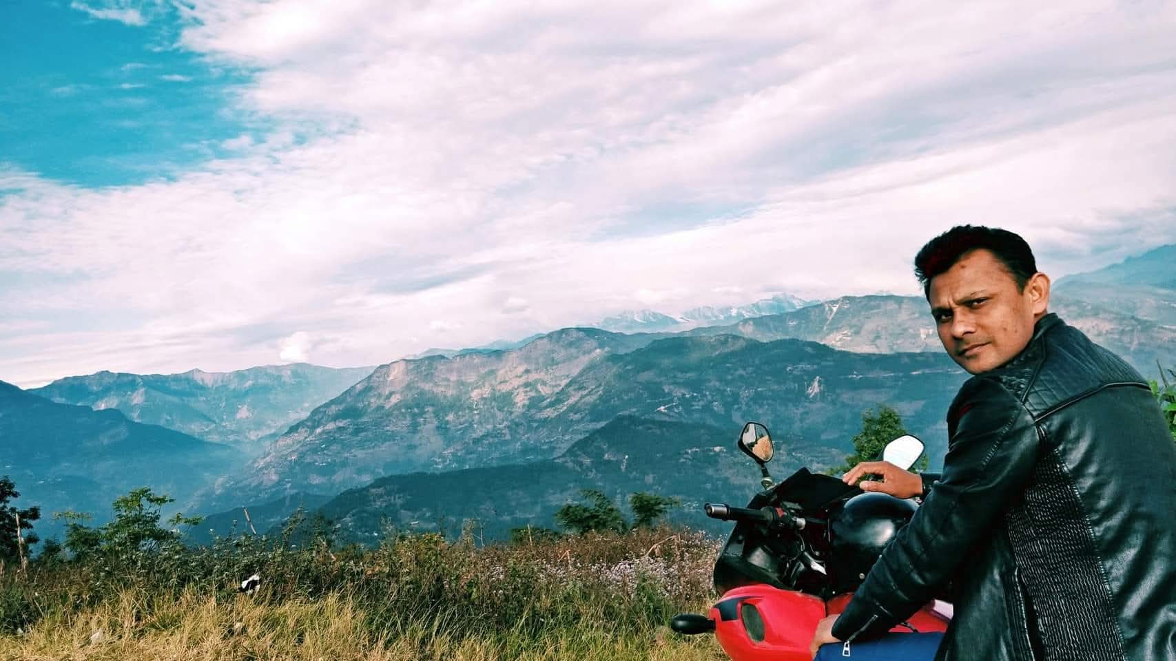 Md. Fakrul Islam on a motorbike with the Himalayan foothills behind him